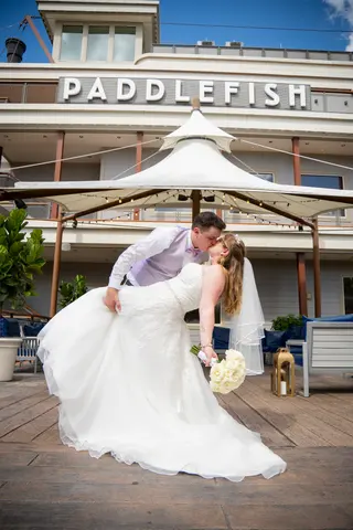 Closer view of newlyweds kissing in front of a riverboat-style building
