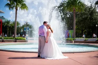 Bride and groom embracing beside a fountain