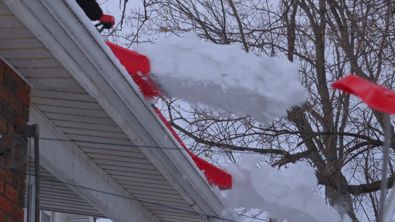 Snow being cleared from a roof in the Frolich Roof Systems & Renovations film